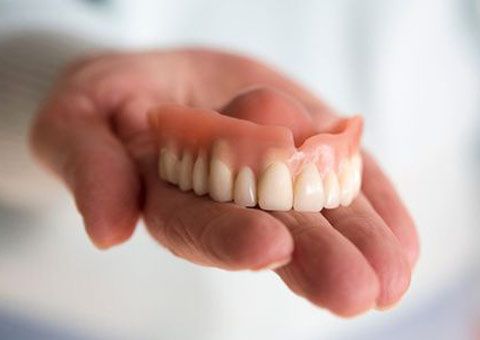 a hand holding an upper full denture